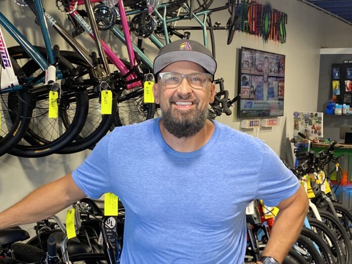 a man standing in a bike shop with his hands on his hips