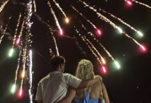 a man and a woman standing in front of a firework display