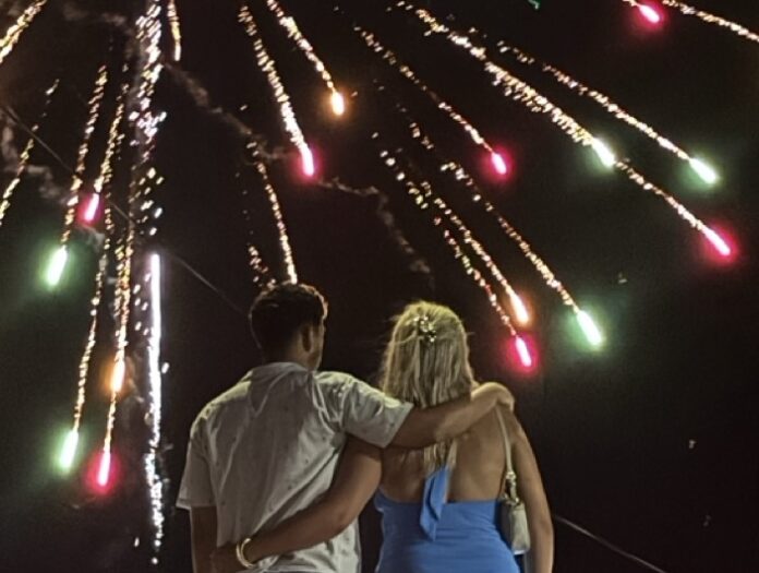 a man and a woman standing in front of a firework display