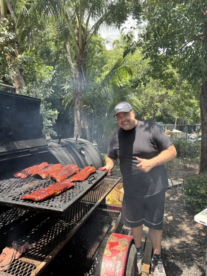 a man standing next to a bbq grill
