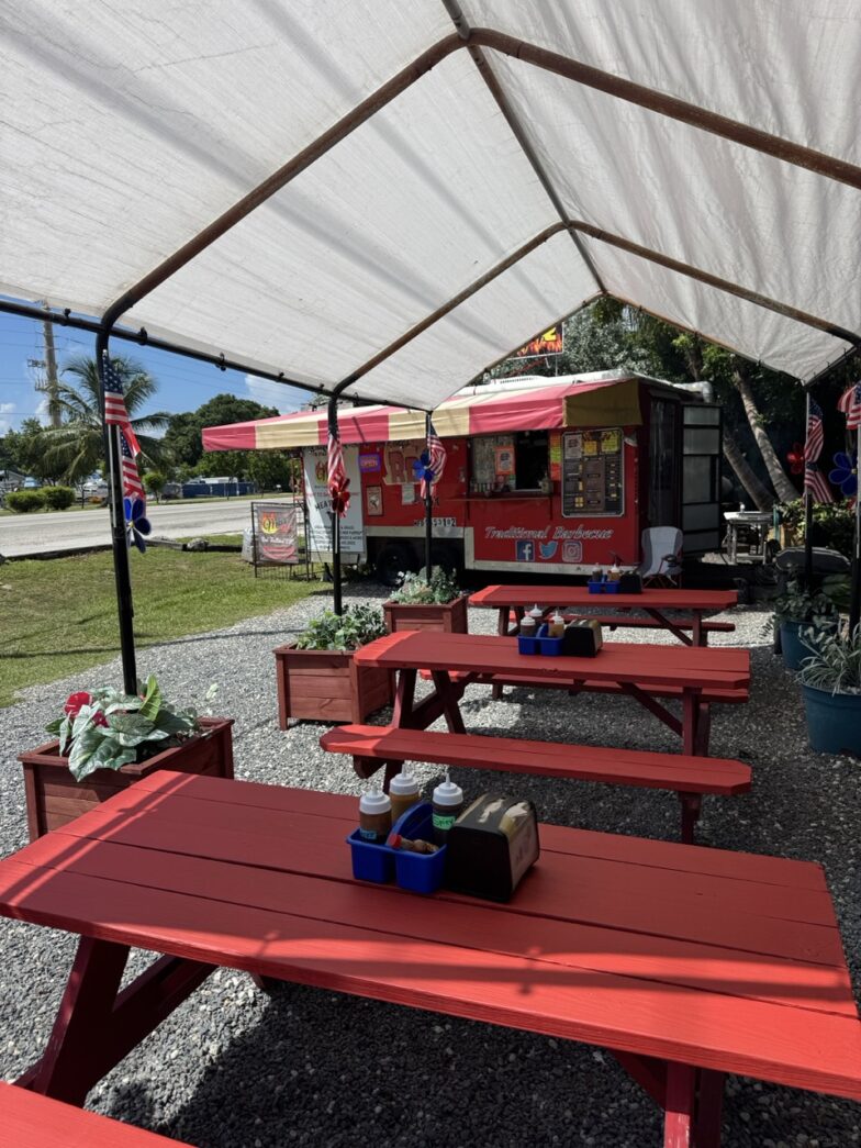 a row of red picnic tables under a tent