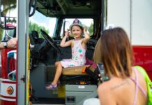 a little girl sitting in the driver's seat of a fire truck
