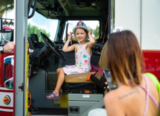 a little girl sitting in the driver's seat of a fire truck