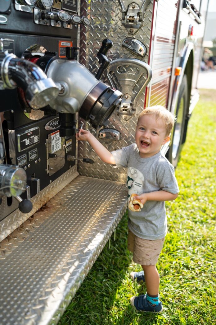 a little boy standing next to a fire truck