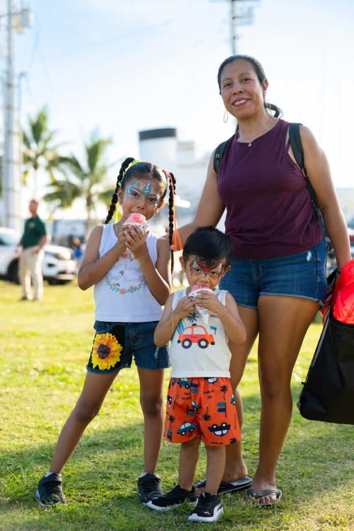 a woman and two children standing in the grass