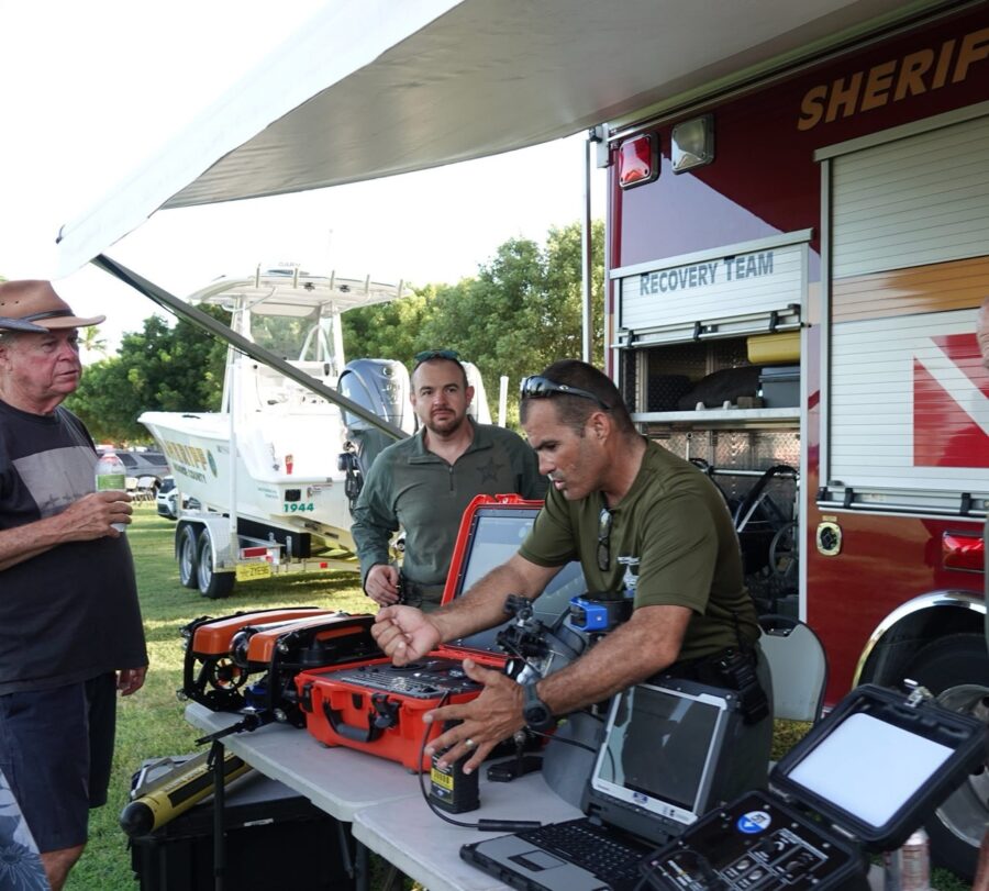 a group of men standing around a table with laptops