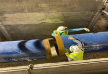 a couple of men standing next to a large pipe