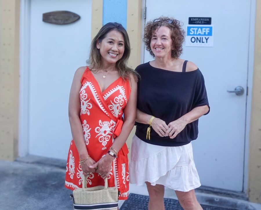 two women standing next to each other in front of a building