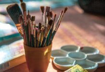 a cup filled with lots of paint brushes on top of a table