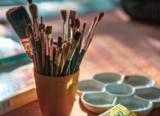 a cup filled with lots of paint brushes on top of a table