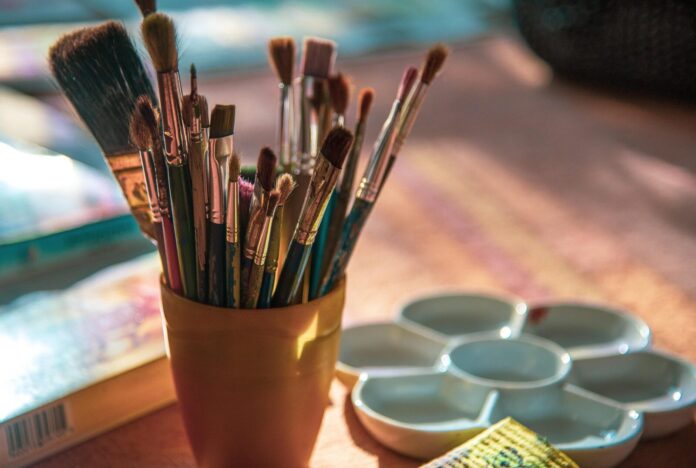 paint-brush-6981008_1920 a cup filled with lots of paint brushes on top of a table