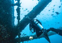 a scuba is looking at a ship wreck in the ocean