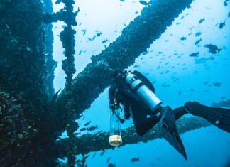a scuba is looking at a ship wreck in the ocean