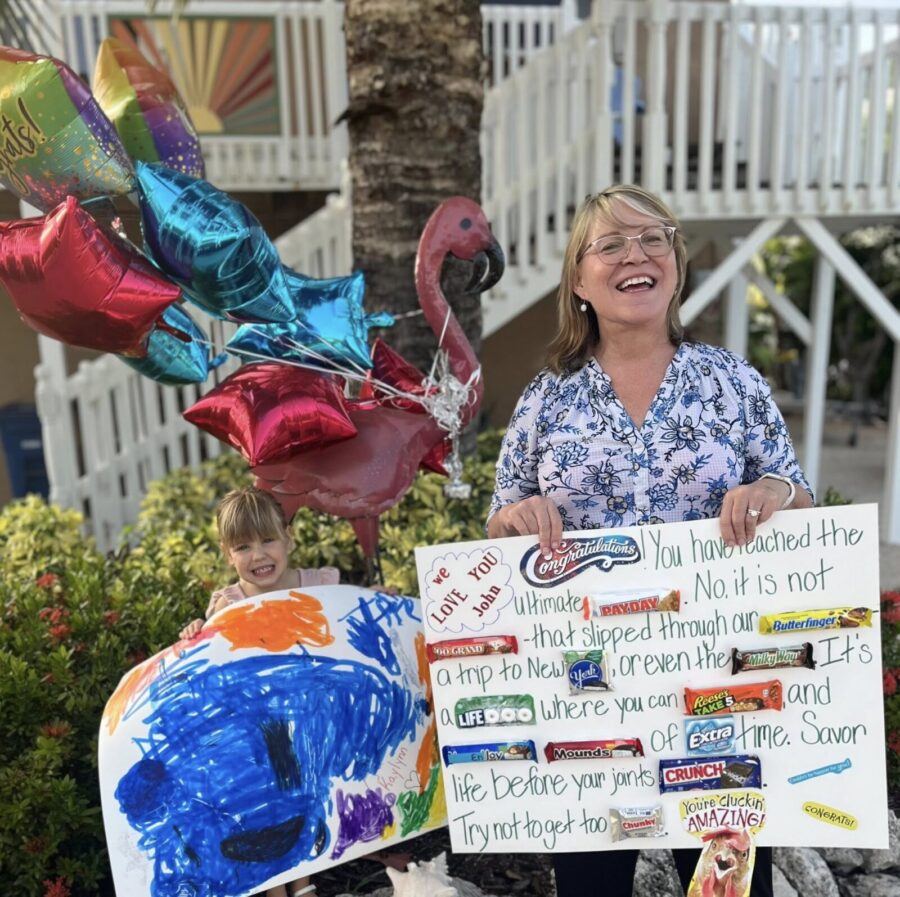 a woman standing next to a child holding a sign