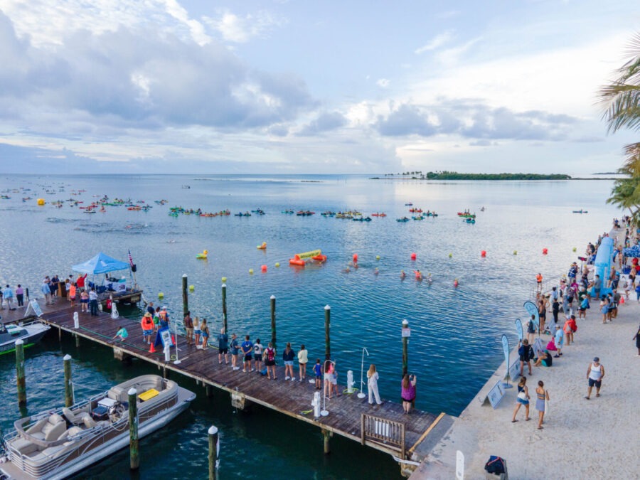a group of people standing on a pier next to a body of water