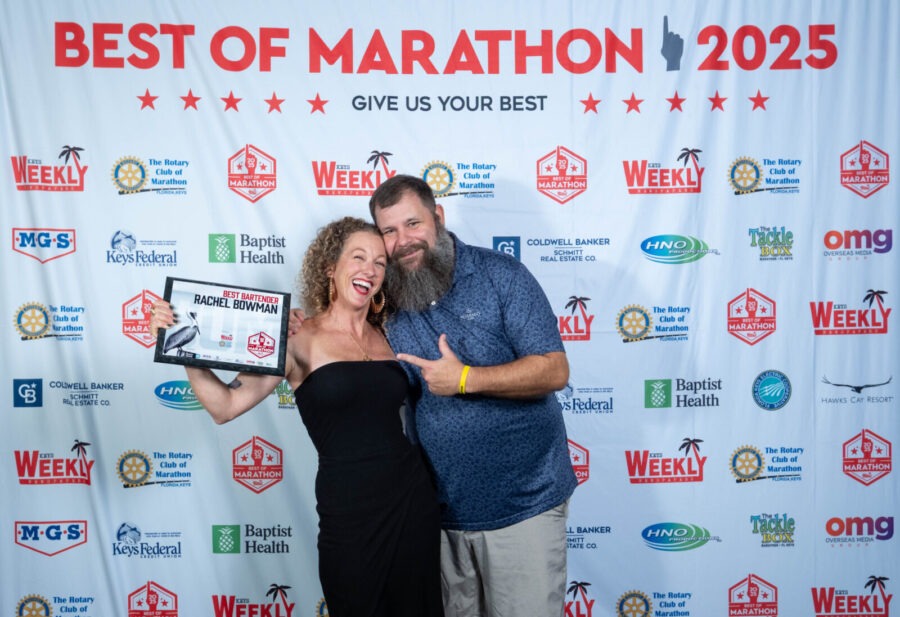 a man and woman posing for a picture with a plaque