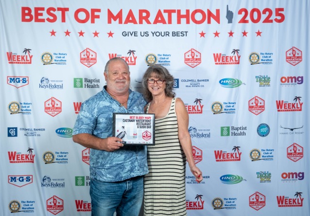 a man standing next to a woman holding a plaque