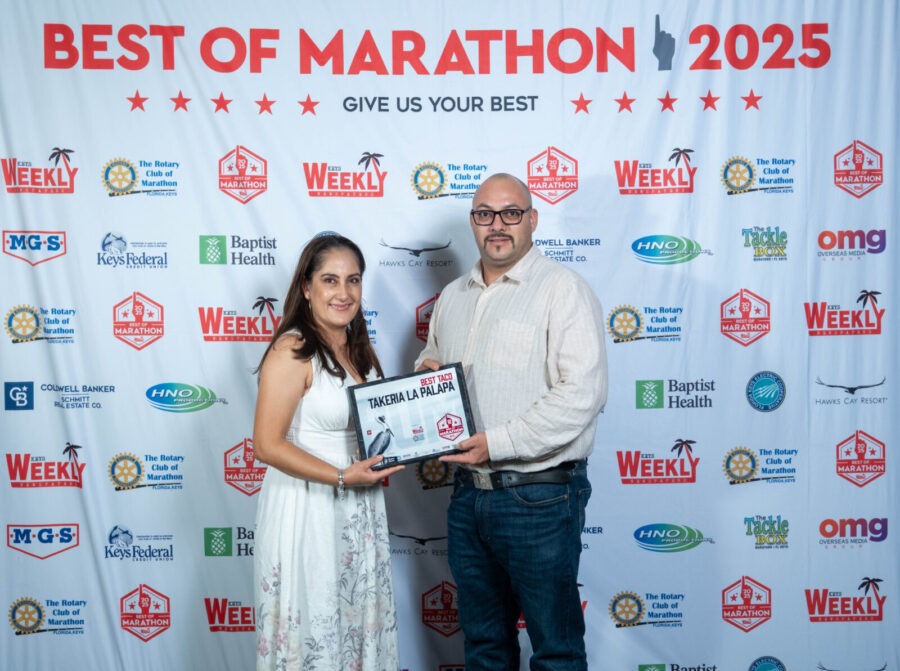 a man standing next to a woman holding a plaque