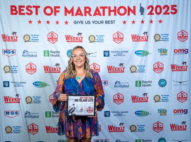 a woman standing in front of a banner holding a plaque