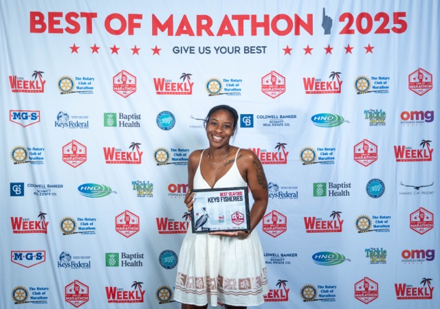 a woman standing on a red carpet holding a plaque