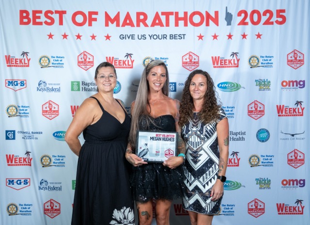 three women posing for a picture in front of a banner