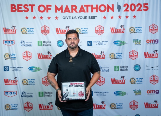 a man standing in front of a wall holding a plaque