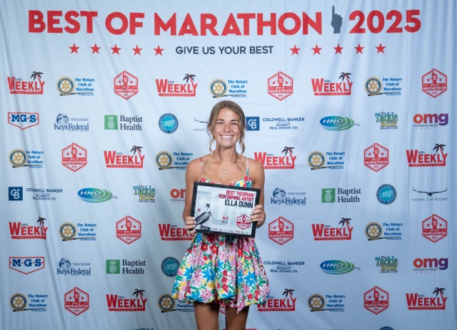a woman standing on a red carpet holding a plaque