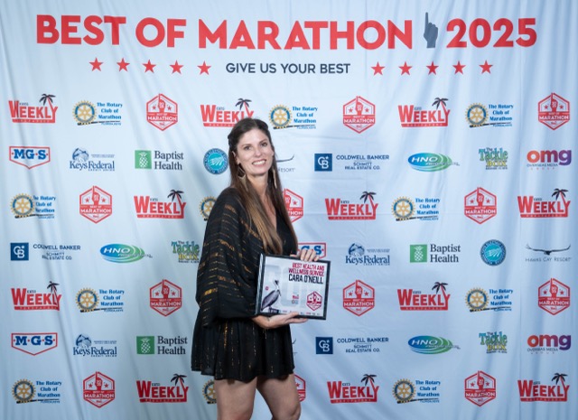 a woman standing on a red carpet holding a plaque