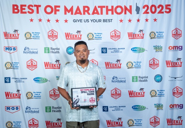 a man standing on a red carpet holding a plaque
