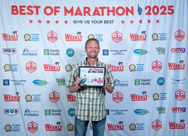 a man standing on a red carpet holding a plaque