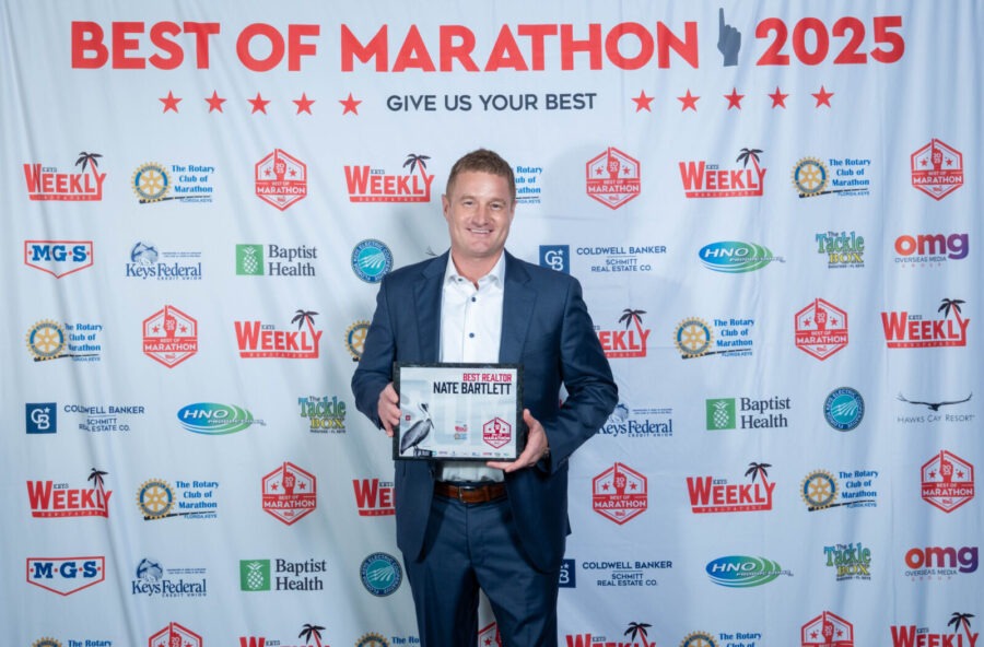 a man standing on a red carpet holding a plaque