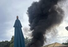 a large black cloud of smoke billows from a building