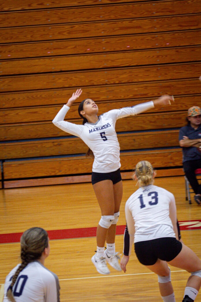 a woman jumping up to hit a volleyball