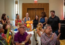 a group of people sitting around a table clapping
