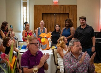 a group of people sitting around a table clapping
