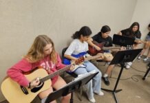 a group of young people playing guitars in a room