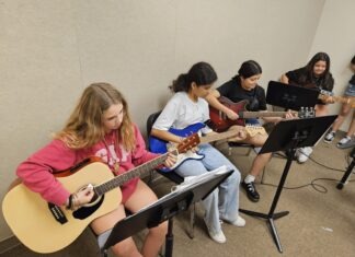 HORACE O’BRYANT LAUNCHES ROCK BAND CLASS WITH DONATED INSTRUMENTS a group of young people playing guitars in a room