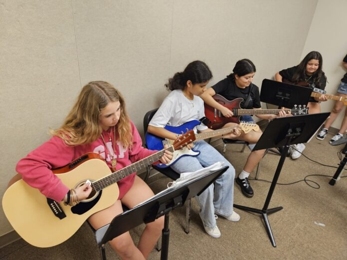 a group of young people playing guitars in a room