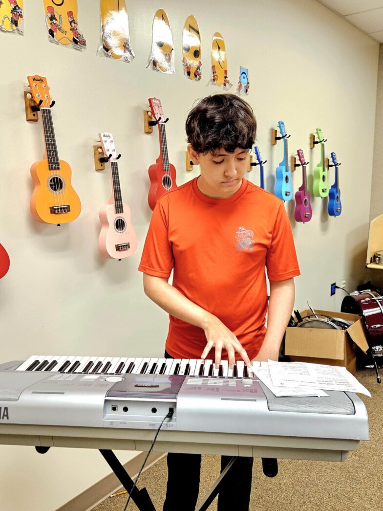 a boy playing a keyboard in a room with guitars on the wall