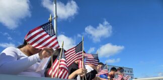 a group of people holding american flags behind a fence