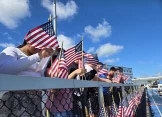 a group of people holding american flags behind a fence