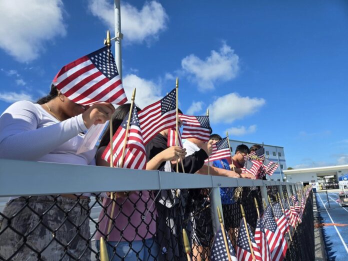 a group of people holding american flags behind a fence