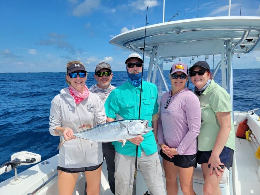 a group of people on a boat holding a fish