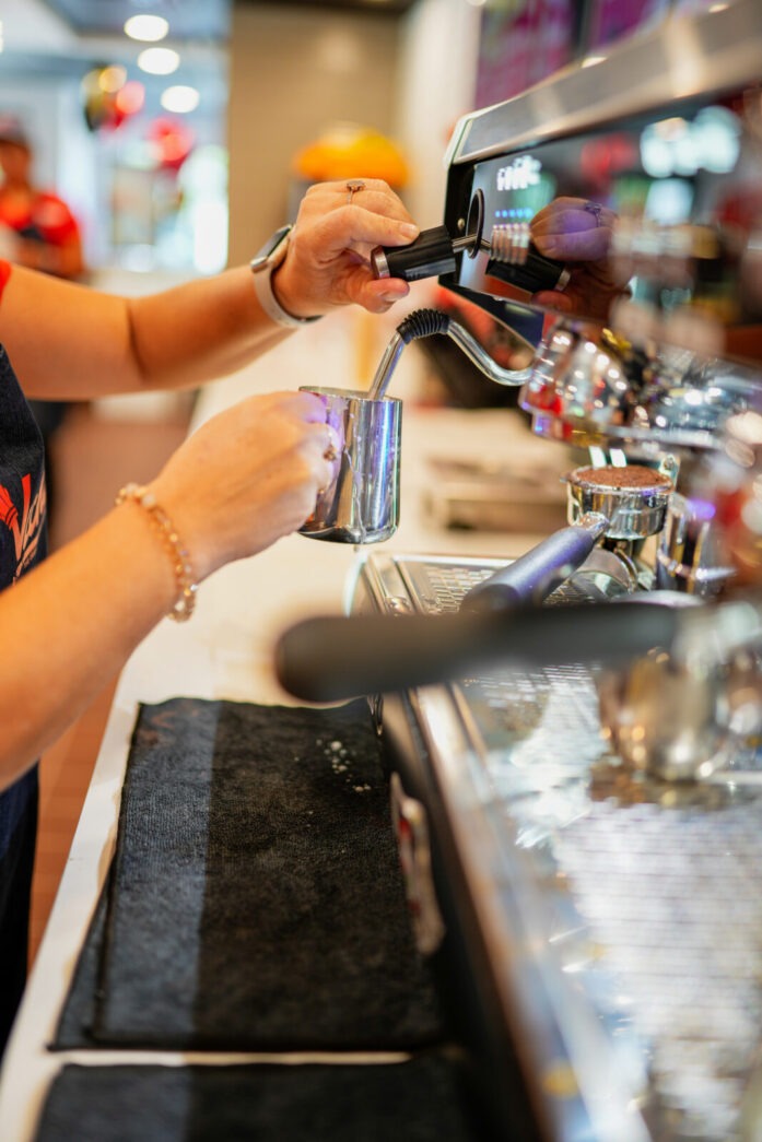 a woman is filling a glass of beer at a bar