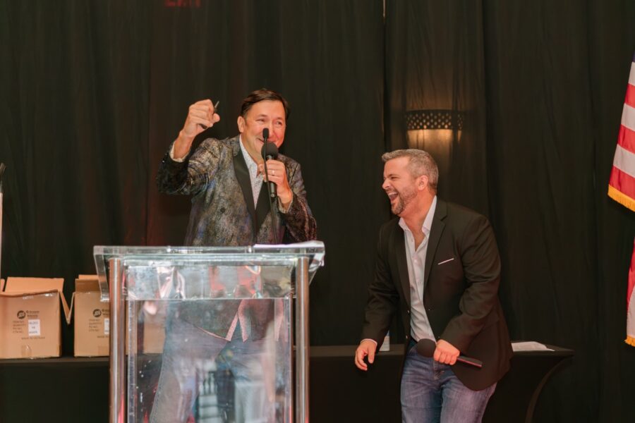 two men standing at a podium giving a speech