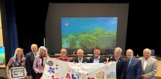 a group of people holding a sign in front of a screen