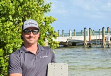 a man holding a laptop computer near a body of water