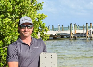a man holding a laptop computer near a body of water