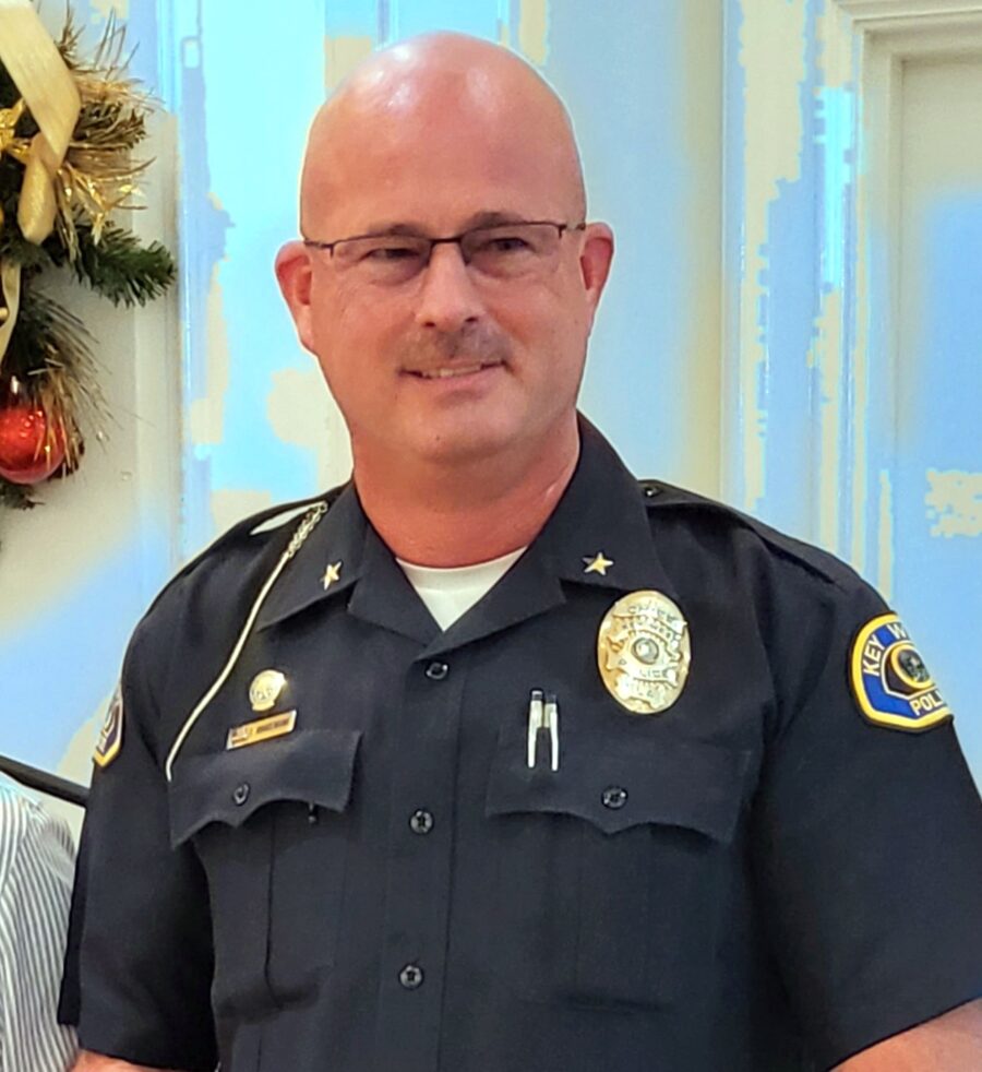 a man in a police uniform standing in front of a christmas wreath