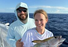 a man and a woman on a boat holding a fish